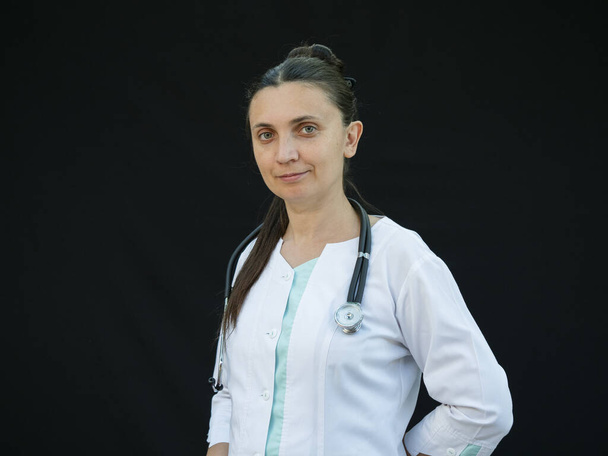 Female doctor shows hand gestures and poses on a black background - Foto, imagen