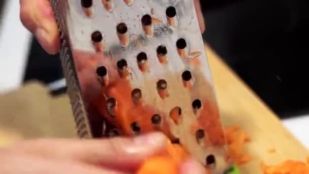 Möhrenraspeln auf einer Reibe in Nahaufnahme. das Konzept des Kochens von Lebensmitteln, Salaten, Suppen - Filmmaterial, Video