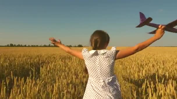 Glückliches Mädchen rennt mit einem Spielzeugflugzeug auf einem Feld im Sonnenuntergang. Kinder spielen Spielzeugflugzeug. Teenager träumt davon zu fliegen und Pilot zu werden. Das Mädchen will Pilotin und Astronautin werden. Zeitlupe - Filmmaterial, Video