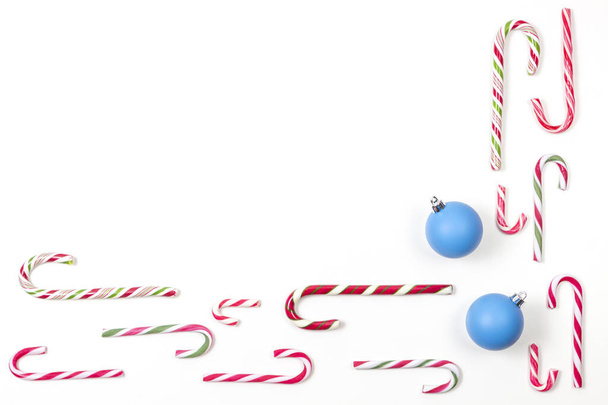 Bastones de caramelo y dos bolas de Navidad azul decoaration bauble marco sobre fondo blanco. Vista superior
 - Foto, Imagen