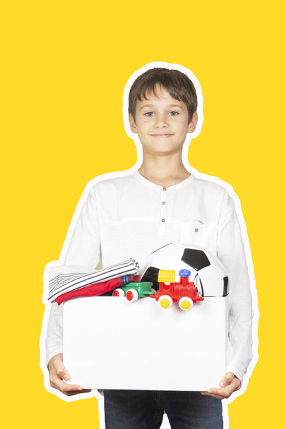 Donation concept. Kid holding donate box with clothes, books, school supplies and toys. Magazine collage style with yellow color background - Fotografie, Obrázek