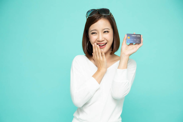 Щаслива азіатка у білій сорочці з кредитною карткою або готівкою.  - Фото, зображення