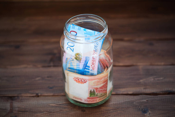 Dinero en un frasco de vidrio sobre un fondo de madera
 - Foto, imagen