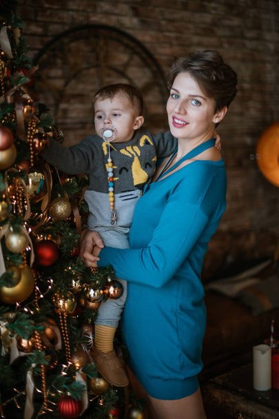 Family New Year. Portrait of mom with baby at the New Year tree at home.  - Фото, изображение