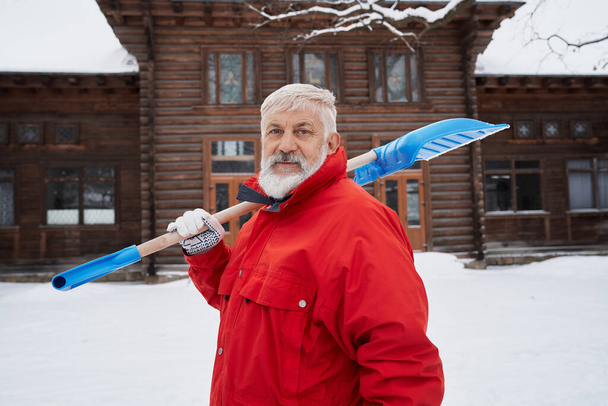 Cleaner with snow shovel on shoulder. - Foto, Imagen