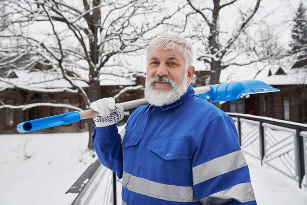 Cleaner in work overalls with shovel for removing snow. - Valokuva, kuva