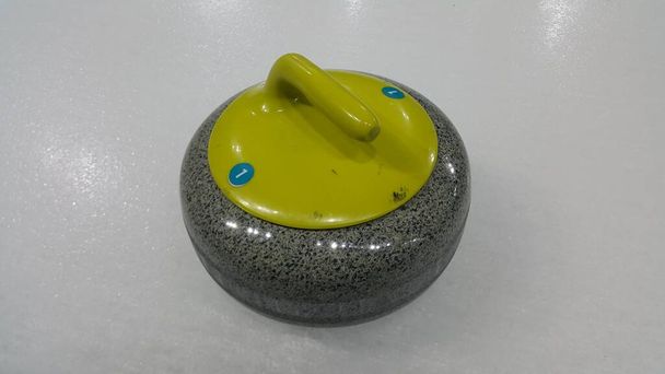 Blick von oben auf einen Curlingstein auf weißem Glatteis - Foto, Bild