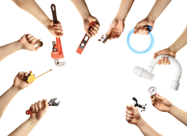 Manos con diferentes herramientas de fontanero sobre fondo blanco
 - Foto, imagen