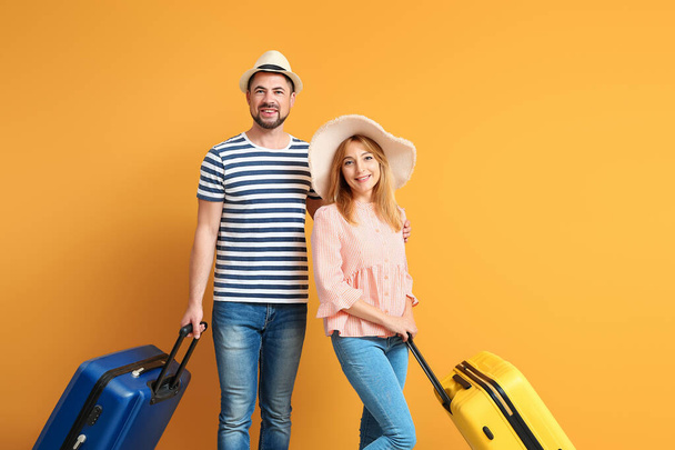 Couple with suitcases on color background - 写真・画像