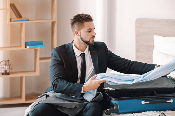 Young man packing things for business trip at home - Photo, Image
