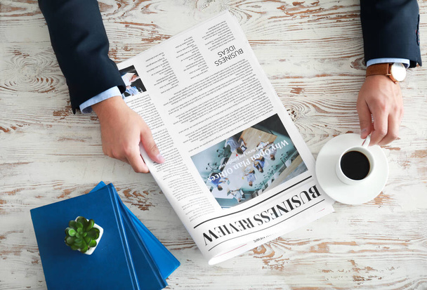Businessman reading newspaper at table - Photo, Image