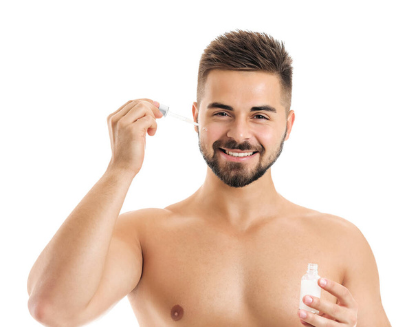 Handsome young man with cosmetic product on white background - Photo, Image