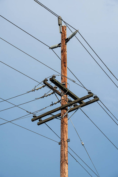 Pólo elétrico e fios, poste elétrico de madeira no fundo do céu azul
. - Foto, Imagem