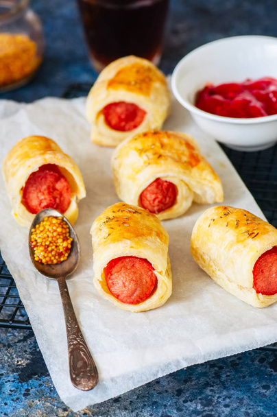 Pigs in a planket - puff pastry rolls with sausages on a wire rack. - Фото, изображение