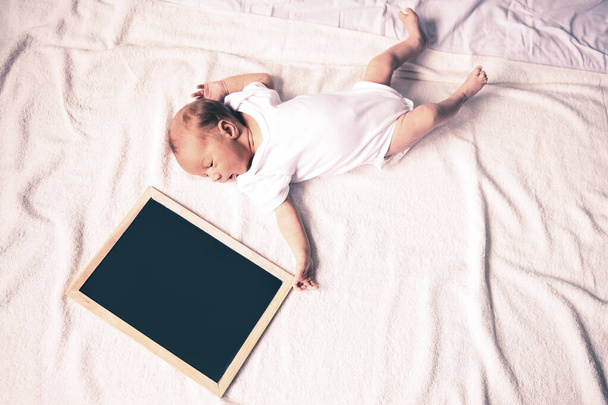 newborn baby with a greeting card lying on the sofa - Zdjęcie, obraz