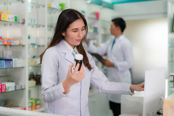 Magabiztos ázsiai fiatal női gyógyszerész mosollyal kezében egy orvostudomány - Fotó, kép