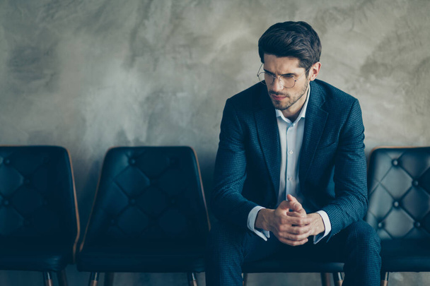 Portrait of sad guy feel nervous wait for meeting with new boss hr interview look pensive minded sit chair wear stylish blazer trousers isolated over grey color background - Foto, Bild