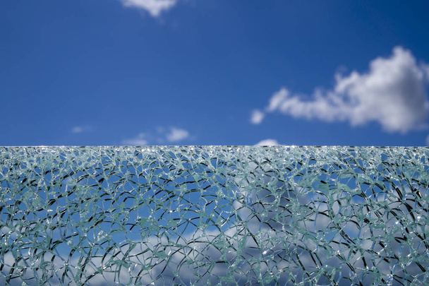 Cracked glass surface against blue sky - Photo, Image