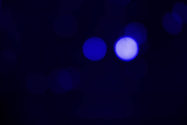 Ontwerpachtergrond. Ronde blauwe bokeh op een zwarte achtergrond - Foto, afbeelding