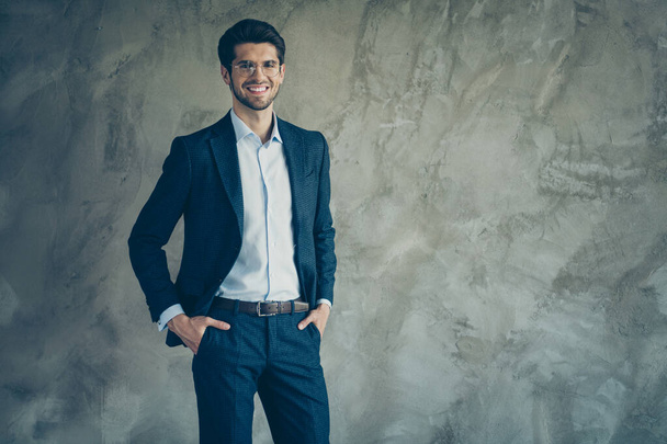 Photo of cheerful positive toothy beaming entrepreneur optimistic friendly looking confidently at you with hands in pockets with stubble isolated grey color background - Foto, Imagen