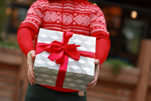 Gros plan de mains masculines et d'une boîte cadeau décorée d'un ruban rouge
 - Photo, image