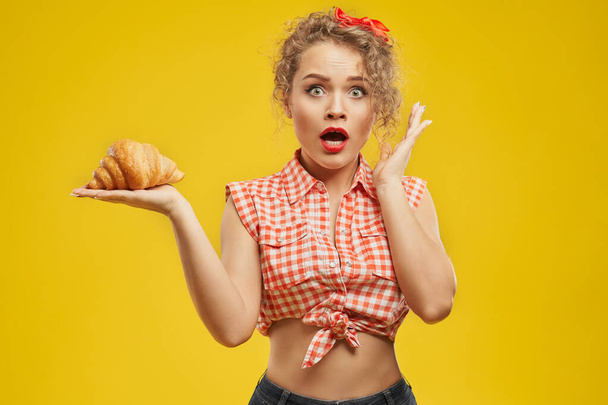 Attractive lady looks shocked of deciding to eat croissant - Foto, imagen