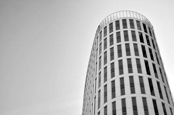 Gordijnwand gemaakt van gehard glas en stalen constructies onder de hemel. Een fragment van een gebouw. Zwart-wit. - Foto, afbeelding