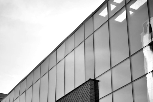 Gordijnwand gemaakt van gehard glas en stalen constructies onder de hemel. Een fragment van een gebouw. Zwart-wit. - Foto, afbeelding