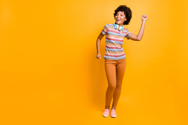 Full length photo of cheerful mulatto girl have headset listen stereo music song dance feel rejoice emotions wear casual style outfit isolated over bright color background - Foto, afbeelding