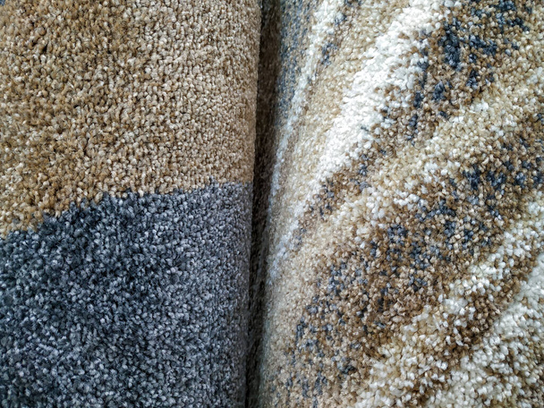 Twee kleurrijke bruinachtige tapijten gerold te koop met close-up op hun zachte en zachte warme textuur patroon gebruikt als interieurdecoratie - Foto, afbeelding