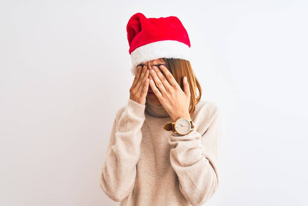 Kaunis punapää nainen yllään joulu hattu yli eristetty tausta hankaus silmät väsymys ja päänsärky, unelias ja väsynyt ilme. Näköhäiriö
 - Valokuva, kuva