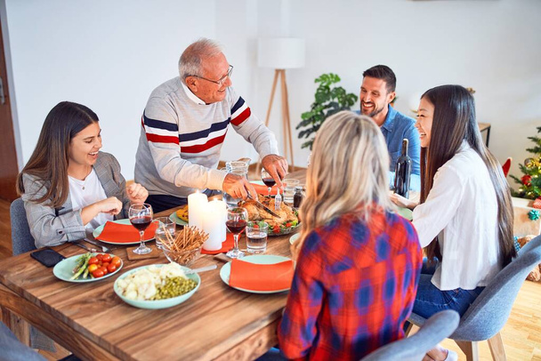 Hermosa reunión familiar sonriendo feliz y confiado. Tallar pavo asado celebrando la Navidad en casa
 - Foto, imagen