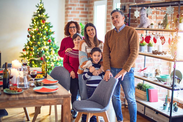 schöne Familie lächelt glücklich und zuversichtlich. Stehen und posieren rund um den Weihnachtsbaum zu Hause - Foto, Bild