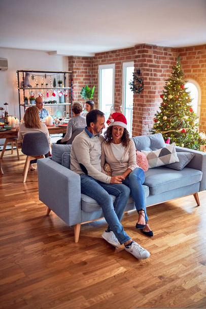 伝統的な料理と装飾でクリスマスの前夜を祝う家で家族や友人の食事、ロマンチックなシニアカップルが一緒にソファに座って話しています - 写真・画像