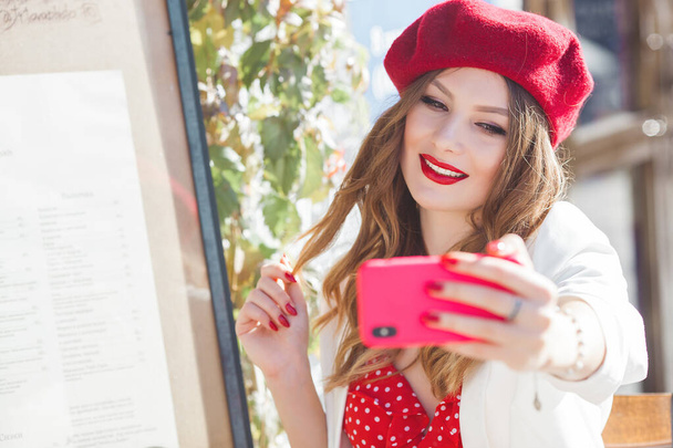 junges attraktives französisches Mädchen macht Selfie auf dem Handy. schöne Frau Nahaufnahme Porträt im Freien in der Cafeteria. hübsche Dame mit Handy. - Foto, Bild