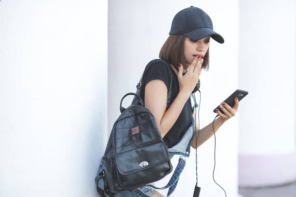 Young attractive woman wearing black and holding gadgets also black. Modern youth. - Photo, Image