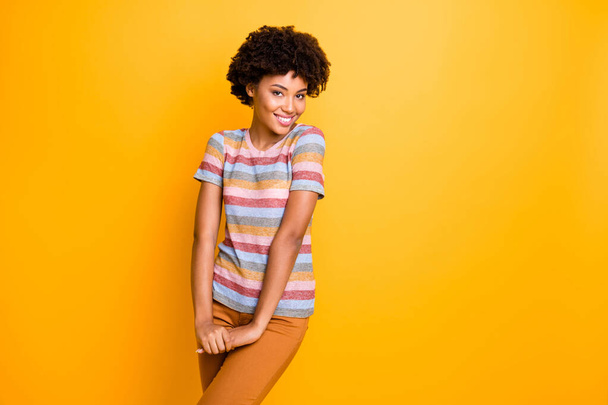 Photo of pretty dark skin lady shy person coquettish mood flirting with handsome guy wear casual striped t-shirt trousers isolated yellow background - Foto, afbeelding
