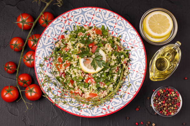 Tabule Salad of bulgur, olive oil, tomato, parsley and spices. on a black background. Eastern cuisine.bulgur dish - Photo, Image