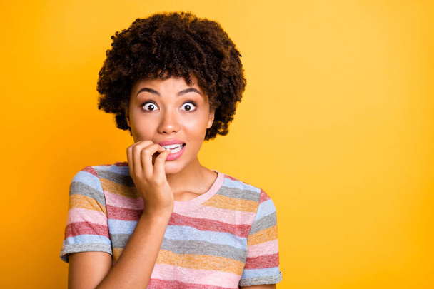 Photo of shocked impressed black girlfriend biting her nails looking at sales she has not expected to see near empty space isolated over vivid yellow color background - Photo, Image