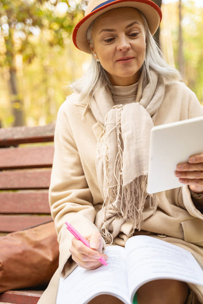 Serious lady doing a grammar exercise outdoors - Photo, image