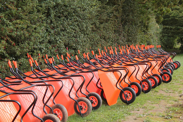 Μια μεγάλη συλλογή από πορτοκαλί πλαστικά τροχοφόρα. - Φωτογραφία, εικόνα