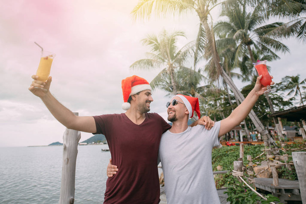 Nuori homo pari cocktaileja joululakit meressä trooppisella saarella
.  - Valokuva, kuva