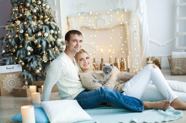 A pair of lovers in anticipation of the celebration of the new year on the background of decorated home interior - Фото, изображение