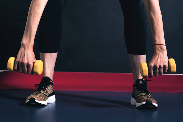 Cropped picture of legs in crouching position with dumbbells in two hands - Fotoğraf, Görsel