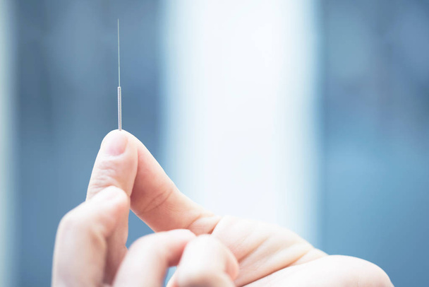 close up of doctors hand showing acupuncture needle - Fotó, kép