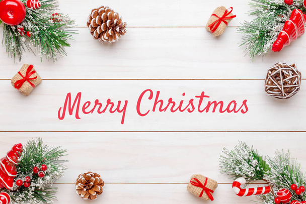 Merry Christmas greeting text on white wooden surface surrounded by Christmas decorations. Top view, flat lay, close-up. - Photo, Image