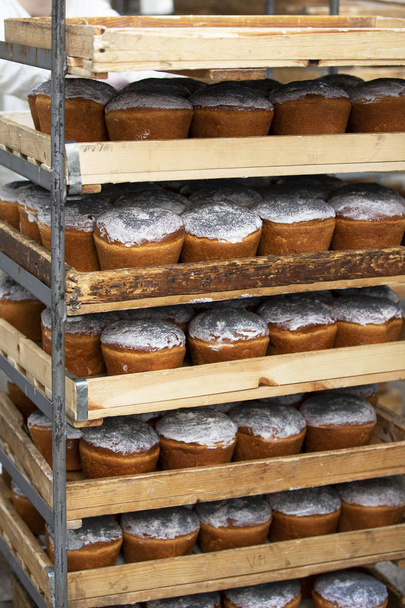 aufrechte Holzpaletten mit gebackenen Ostereiern. industrielle Produktion von Osterkuchen. Bäckerei. - Foto, Bild