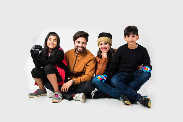 Indian family in warm clothes sitting against white background. Ready for winter concept - Photo, Image