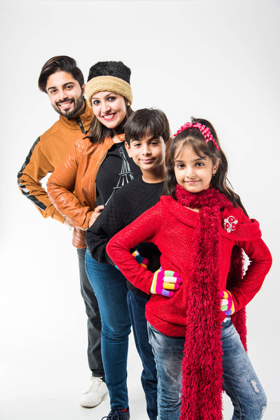 Studioporträt einer glücklichen indischen Familie in warmer Kleidung, die vor weißem Hintergrund steht. Bereit für das Winterkonzept - Foto, Bild
