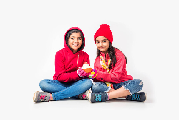 Zwei kleine indische Mädchen in warmer Kleidung vor weißem Hintergrund - Foto, Bild